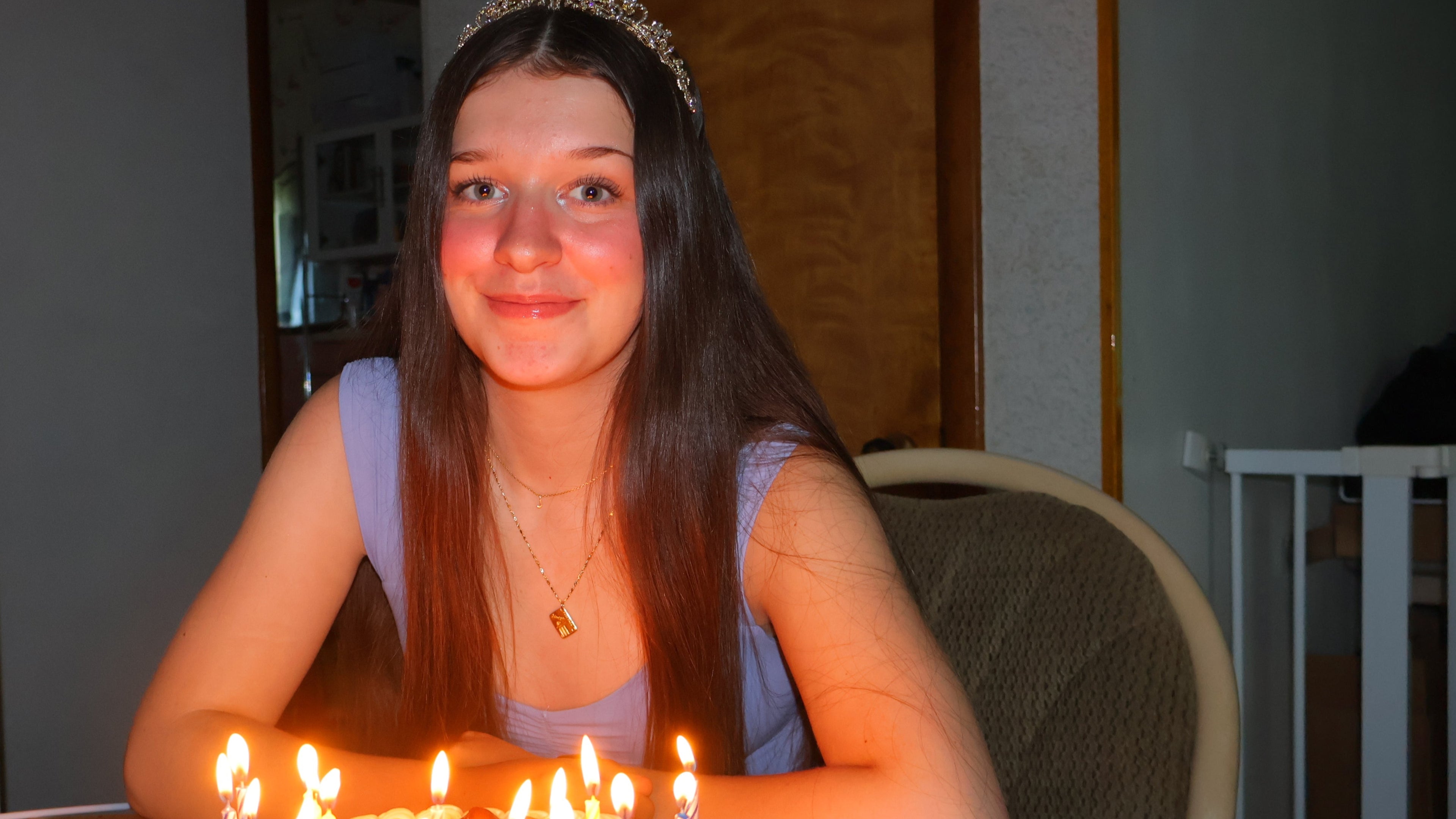 Young woman celebrating a birthday with lit candles on a cake, indoors.